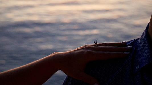 woman holding man's right shoulder near body of water thumbnail