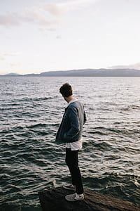 man standing on rock near sea thumbnail