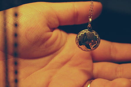 Person Holding Round Silver-colored Necklace Pendant thumbnail