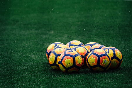 yellow-and-orange Nike soccer balls on green grass at daytime thumbnail