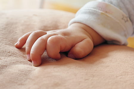 baby's right hand on brown suede textile thumbnail