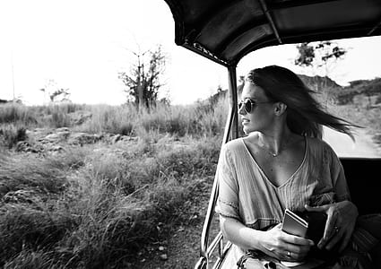 grayscale photography of woman riding on vehicle looking on her right side thumbnail