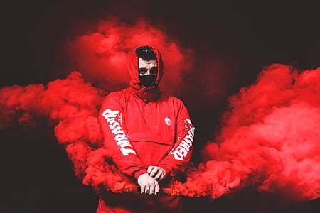 man wearing red hoodie holding red smoke maker device thumbnail