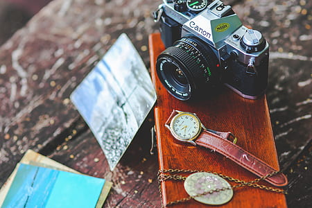 close-up photo of black and gray Canon camera beside watch and necklace thumbnail