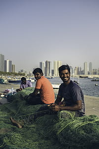 Three Men Sitting on Dock Holding Fishing Net thumbnail