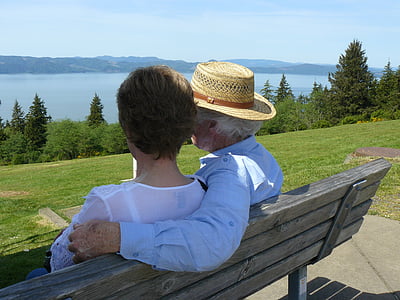 man in blue long-sleeved top beside woman in white top sitting in brown bench thumbnail