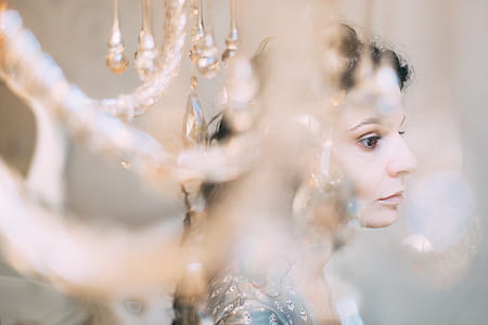 selective focus photography of woman behind chandelier thumbnail