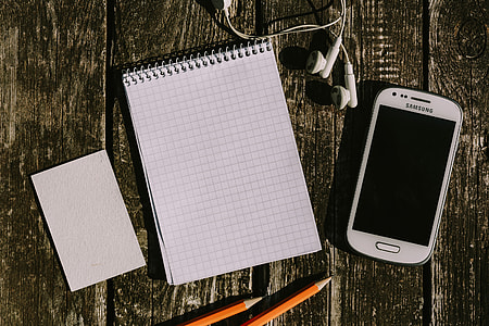 White smartphone with various items on a wooden background thumbnail