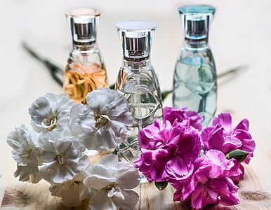 selective focus photography of three spray bottles behind pink and white petaled flowers thumbnail
