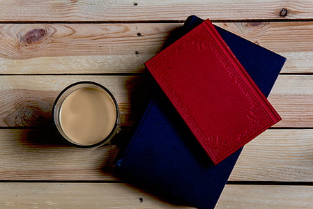 red book on top of blue book beside cup thumbnail