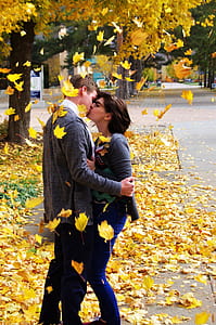 woman and man kissing near trees during daytime thumbnail