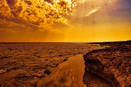 photo of body of water beside cliff during golden hour thumbnail