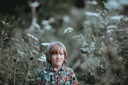selective focus photography of smiling boy surrounded with white flowers thumbnail