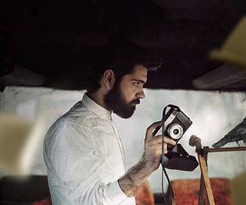 man holds black and gray camera thumbnail
