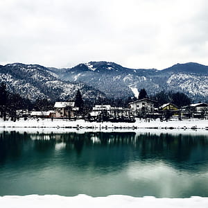 White Houses in Front of Mountains Under White Cloudy Sky thumbnail
