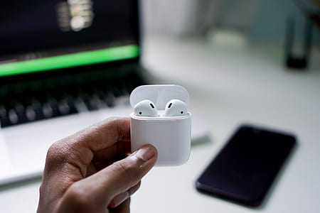 person holding white Apple AirPods with charging case thumbnail