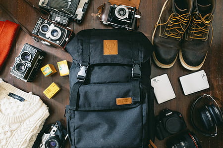 black backpack and pair of black sneakers on brown floor thumbnail