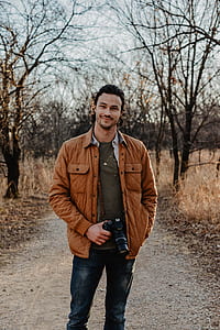man standing in the middle of road while holding DSLR camera thumbnail