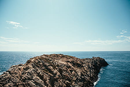 A rocky cliff in the ocean with horizon in the background thumbnail