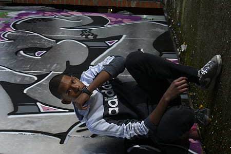 man squatting beside graffiti art thumbnail