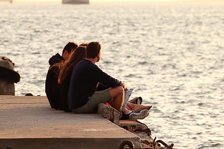 two men and woman sitting on sea dock thumbnail