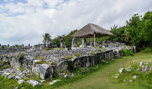 brown cottage on rock formation under white clouds thumbnail