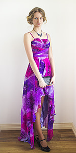 woman in purple spaghetti strap dress standing in front of white painted wall thumbnail