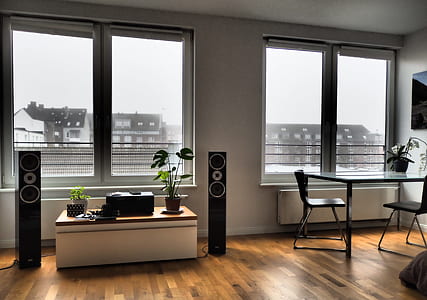 white wooden desk in between two black tower speakers thumbnail