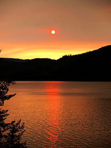 silhouette of mountain across body of water during golden hour thumbnail