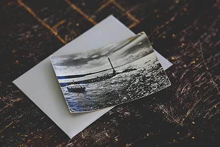 boat on body of water portrait photo on brown wooden board thumbnail