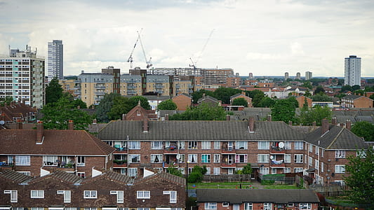 Brown and White Wall Paint Houses Beside Green Trees Near High Rise Building thumbnail