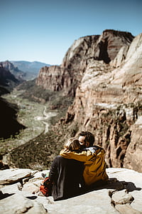 man and woman sitting on mountain cliff during daytime thumbnail
