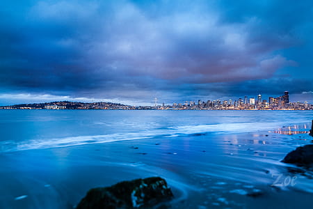 City Buildings Near Body of Water Under Gray Clouds thumbnail