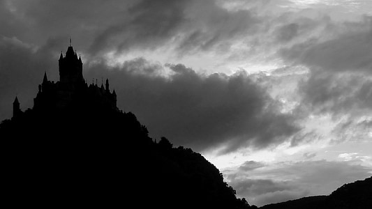 silhouette of castle on top of mountain under cloudy sky thumbnail