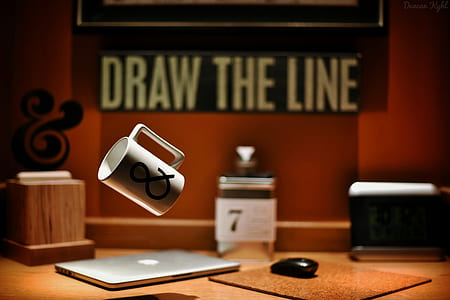 black and white ceramic mug with ampersand logo-printed floating near silver MacBook and black wireless computer mouse thumbnail