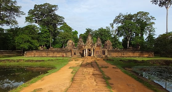 brown concrete temple beside woods under blue skies thumbnail