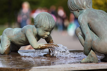 close-up photography of statue of child covering fountain with her hand during daytime thumbnail