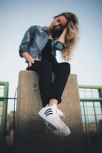 woman sitting on brown concrete fence thumbnail