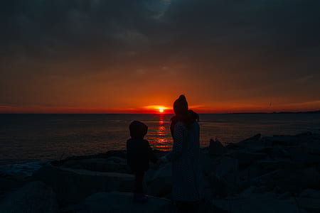 two silhouette of people near seashore during golden hour thumbnail