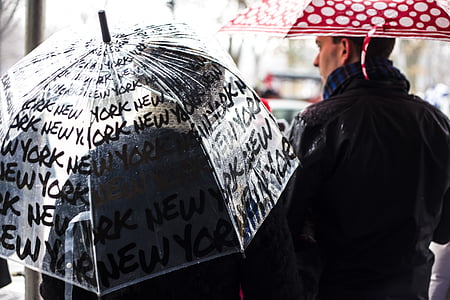 person holding clear umbrella near man wearing black jacket holding red umbrella at daytime thumbnail