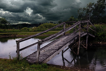 gray wooden bridge under gray clouds during daytime thumbnail