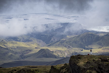 person standing of mountain under cloudy sky thumbnail
