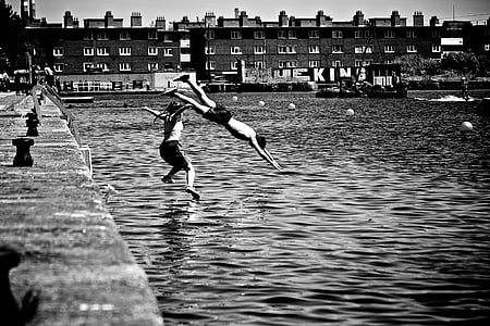 grayscale photo of two person diving on body of water thumbnail