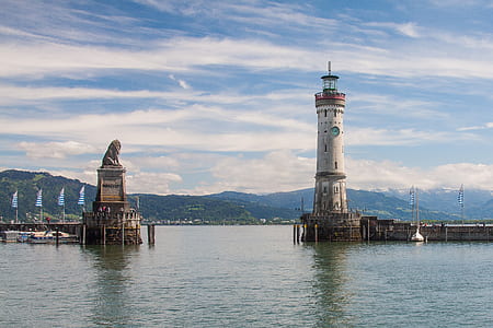 lighthouse near lion statue on body of water thumbnail