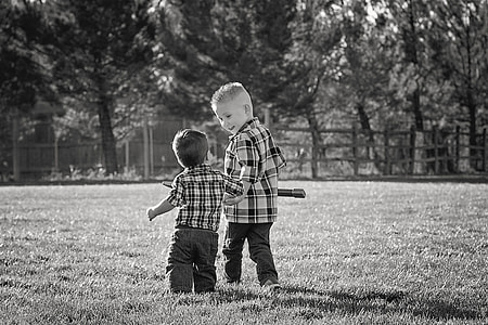 gray scale photography of two children walking through the field during daytime thumbnail