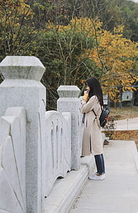 woman with backpack standing near concrete railings and trees thumbnail