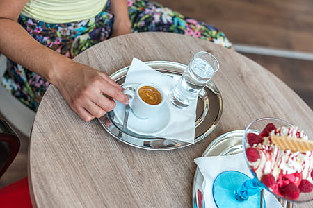 Person Sitting Beside Table While Holding Cup of Coffee thumbnail