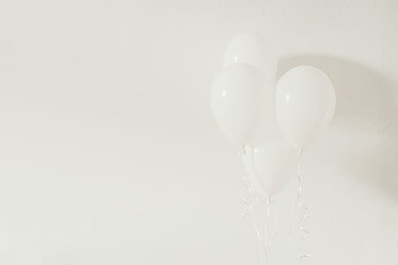 three floating white balloons behind white wall thumbnail