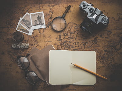 black MILC camera beside magnifying glass on brown map printed surface thumbnail