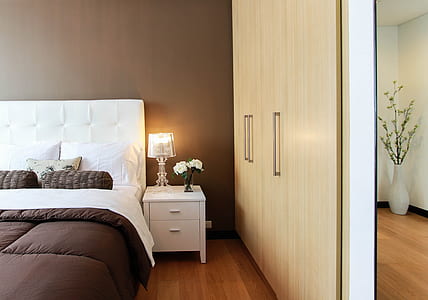 brown wooden wardrobe near white wooden nightstand with lighted table lamp thumbnail